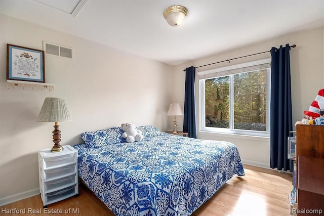 bedroom with baseboards, wood finished floors, and visible vents