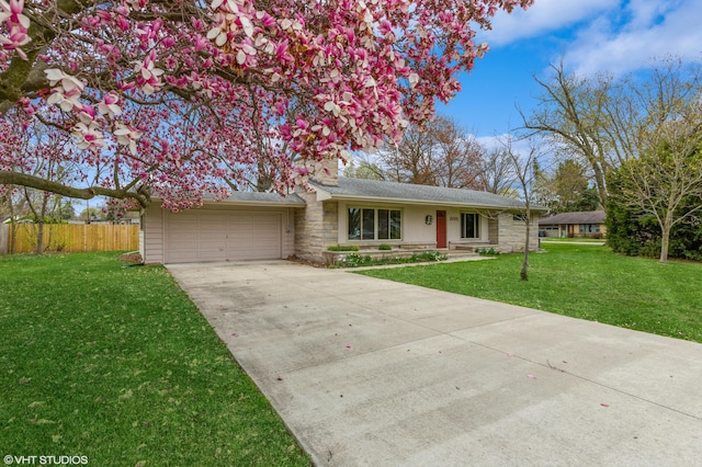 3105 Kevin St, Saint Joseph, MI 49085 - view of front of property with fence, an attached garage, driveway, stone siding, and a front yard