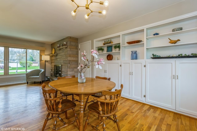 3105 Kevin St, Saint Joseph, MI 49085 - dining area featuring a baseboard heating unit, a chandelier, light wood-style floors, and a fireplace