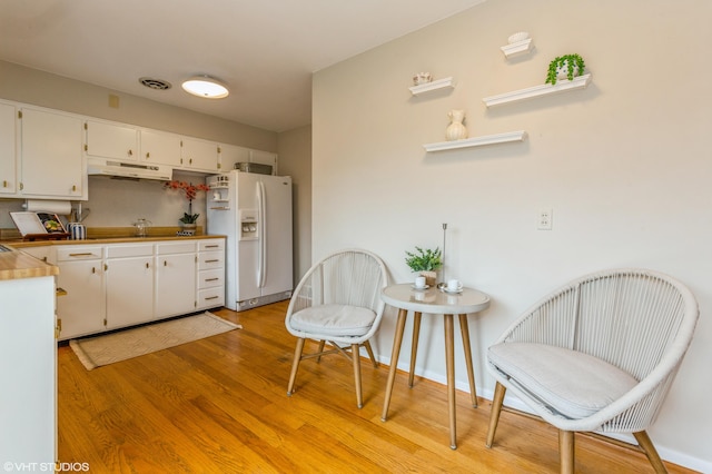 3105 Kevin St, Saint Joseph, MI 49085 - kitchen with white cabinets, light wood finished floors, under cabinet range hood, visible vents, and white refrigerator with ice dispenser