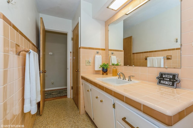 3105 Kevin St, Saint Joseph, MI 49085 - bathroom with speckled floor, wainscoting, vanity, and tile walls