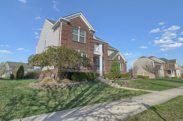 traditional-style home featuring brick siding, a balcony, and a front yard