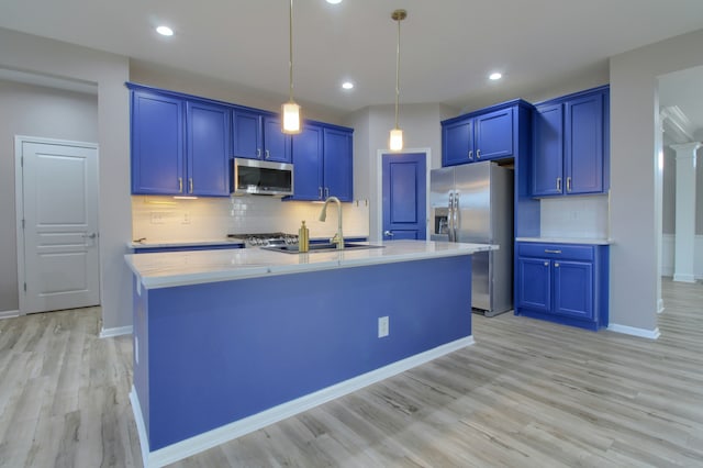 kitchen featuring blue cabinetry, stainless steel appliances, light countertops, and a sink