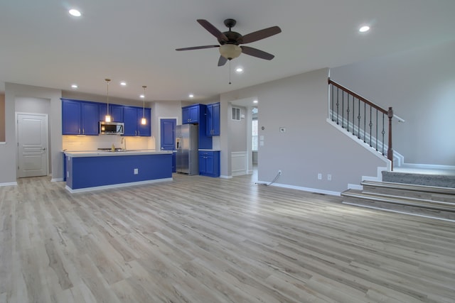 unfurnished living room featuring light wood finished floors, recessed lighting, ceiling fan, and stairway
