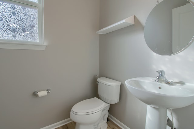 bathroom featuring baseboards, wood finished floors, toilet, and a sink