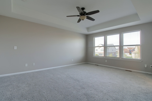 unfurnished room featuring baseboards, light carpet, ceiling fan, and a tray ceiling
