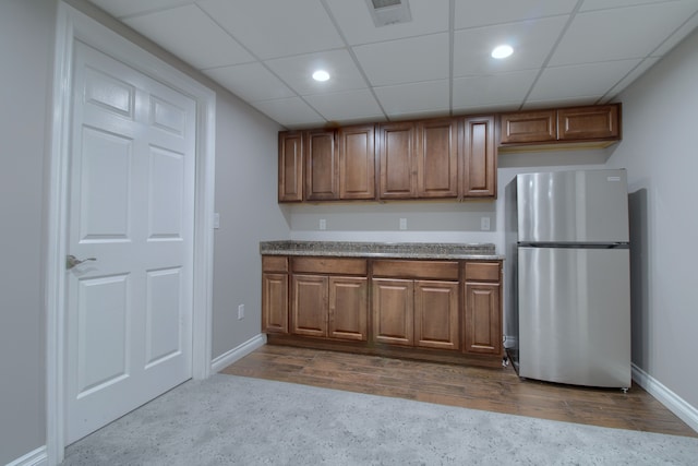 kitchen featuring brown cabinets, visible vents, freestanding refrigerator, baseboards, and dark wood-style flooring