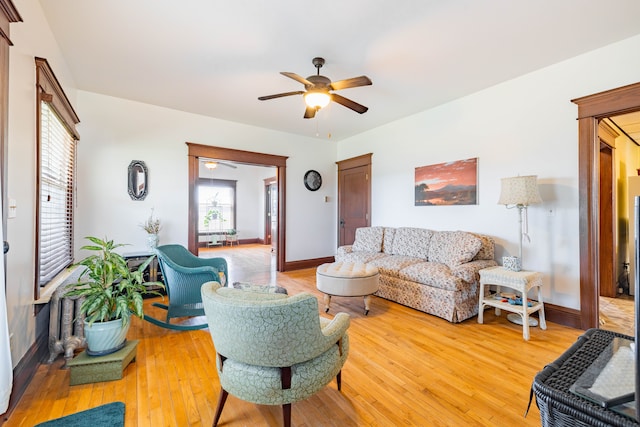 living room featuring a ceiling fan, light wood-style flooring, and baseboards