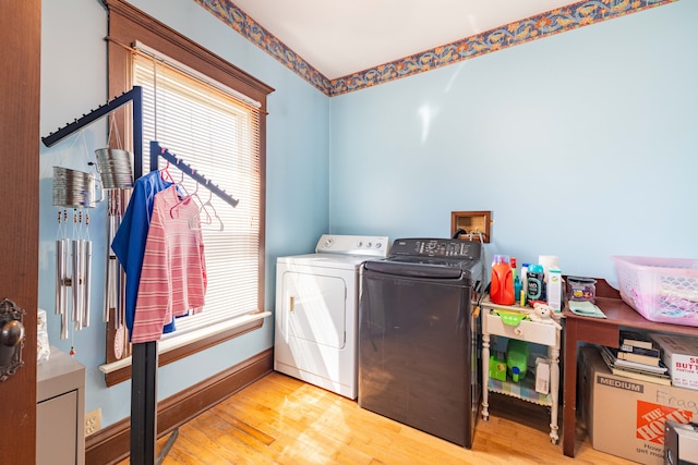 washroom with a wealth of natural light, wood finished floors, laundry area, and washing machine and dryer