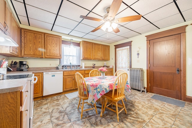 kitchen with a sink, range with electric cooktop, white dishwasher, radiator heating unit, and light countertops