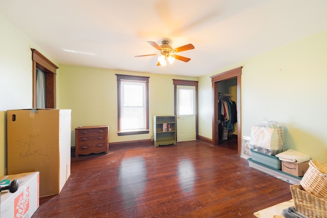 interior space with wood finished floors, a ceiling fan, and baseboards