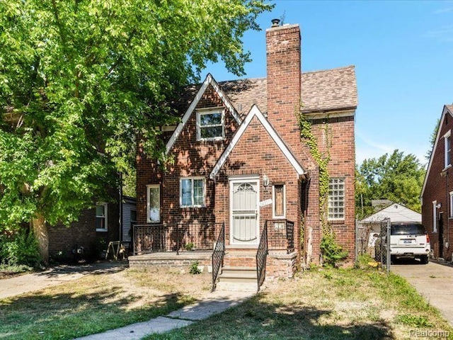 english style home featuring a chimney and brick siding