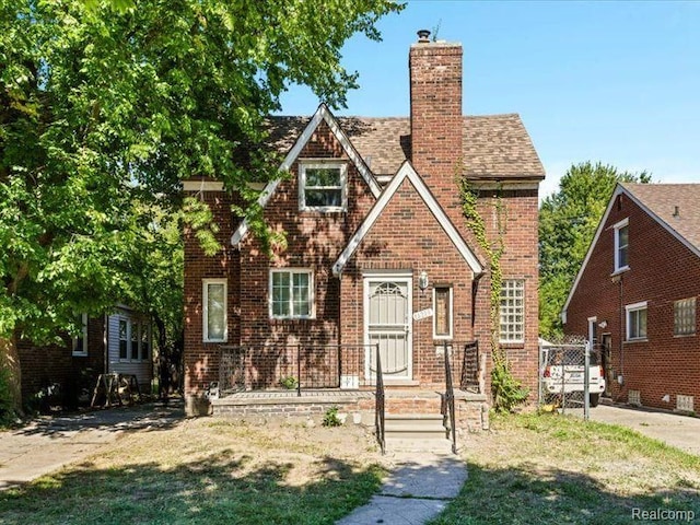 english style home with brick siding and a chimney