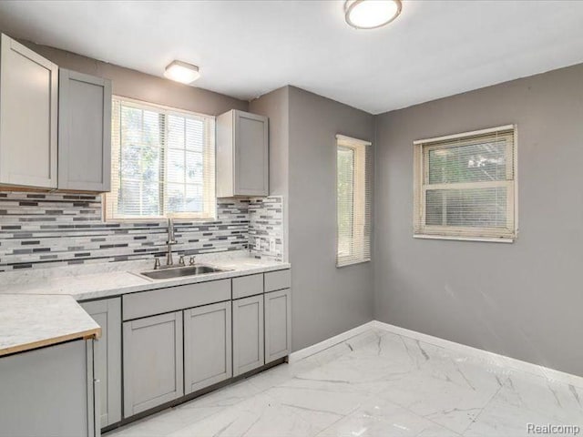 kitchen featuring baseboards, a sink, marble finish floor, and gray cabinets