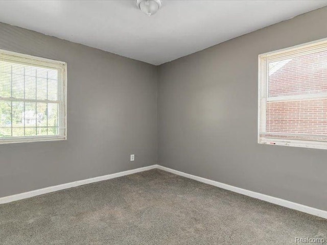 carpeted spare room featuring a wealth of natural light and baseboards
