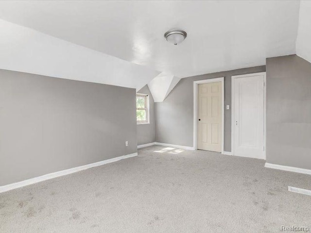 additional living space featuring carpet, lofted ceiling, and baseboards