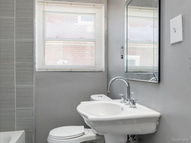 full bath with toilet, a tub to relax in, and a sink