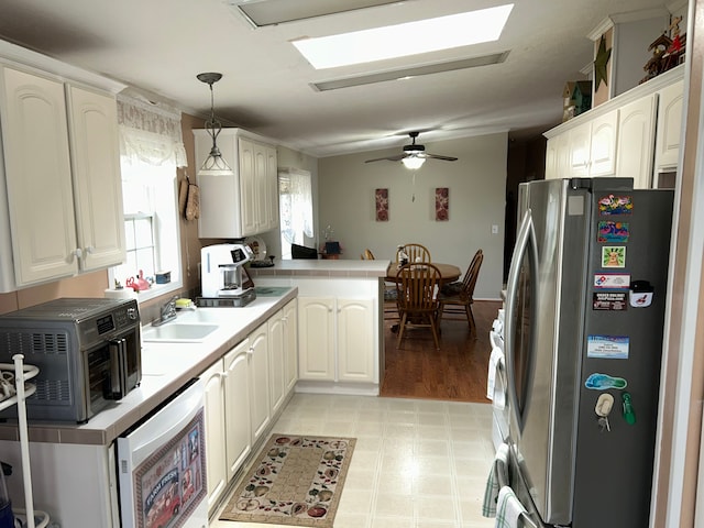 326 Basket Br, Oxford, MI 48371 - kitchen featuring a sink, freestanding refrigerator, a skylight, a peninsula, and hanging light fixtures