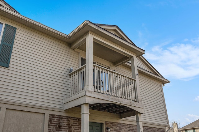 view of side of home featuring a balcony and brick siding
