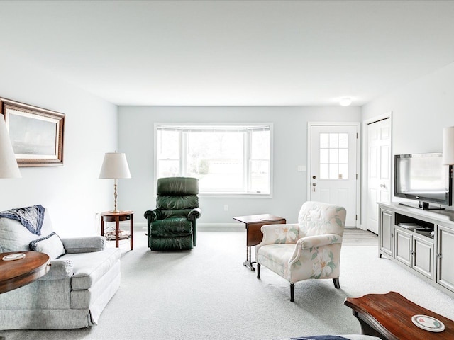 living area with baseboards, a wealth of natural light, and light colored carpet
