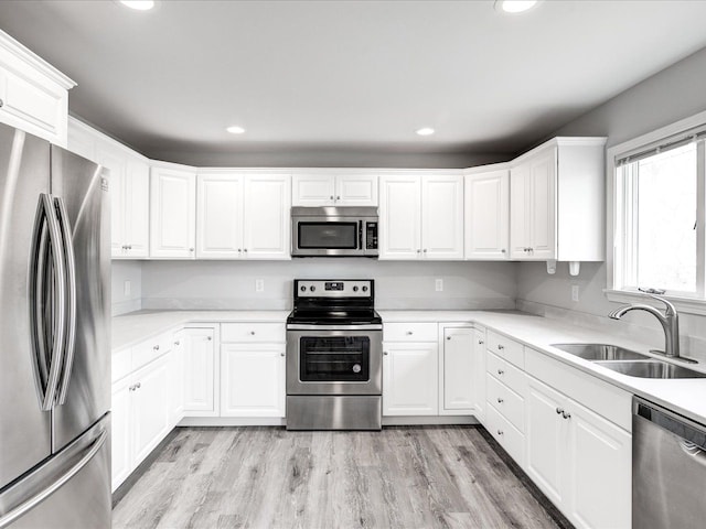 kitchen featuring appliances with stainless steel finishes, recessed lighting, white cabinets, and a sink