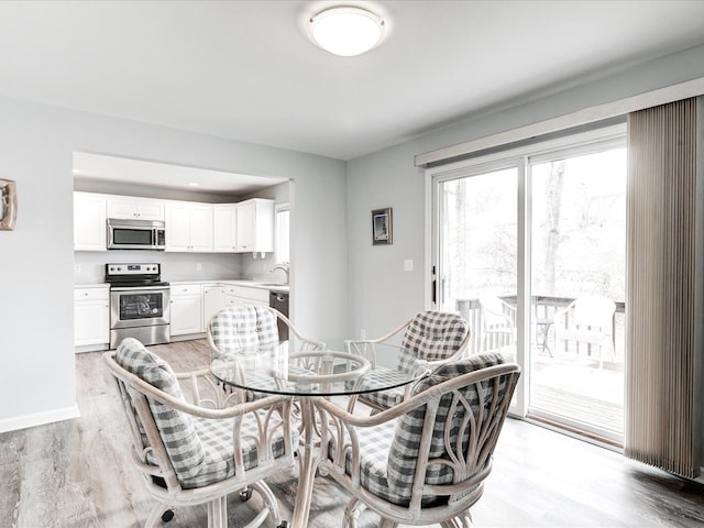 dining space with light wood-style flooring and baseboards