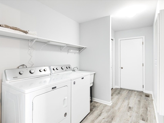 laundry area featuring washer and clothes dryer, baseboards, laundry area, and light wood-style flooring