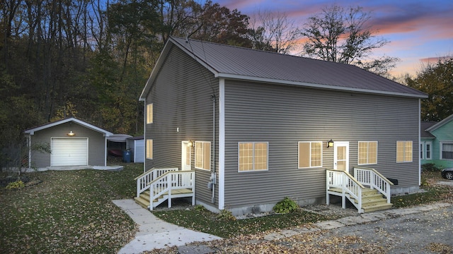 view of front of property featuring an outdoor structure, a detached garage, a front lawn, and metal roof