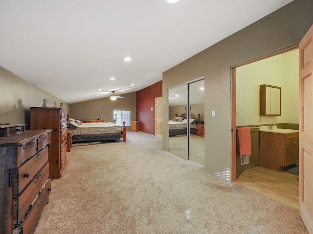 bedroom featuring vaulted ceiling, a closet, light carpet, and a sink