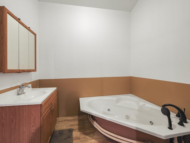 full bathroom featuring a tub with jets, vanity, and wood finished floors