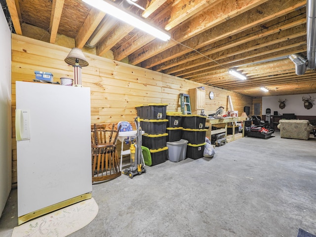 unfinished basement featuring freestanding refrigerator