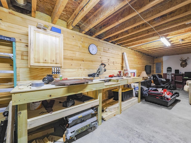 interior space featuring concrete floors, wooden walls, electric panel, and a workshop area
