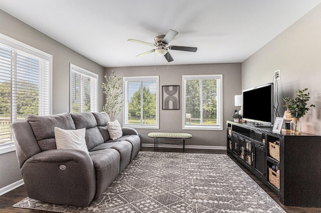 living room featuring a ceiling fan, baseboards, and dark wood-type flooring