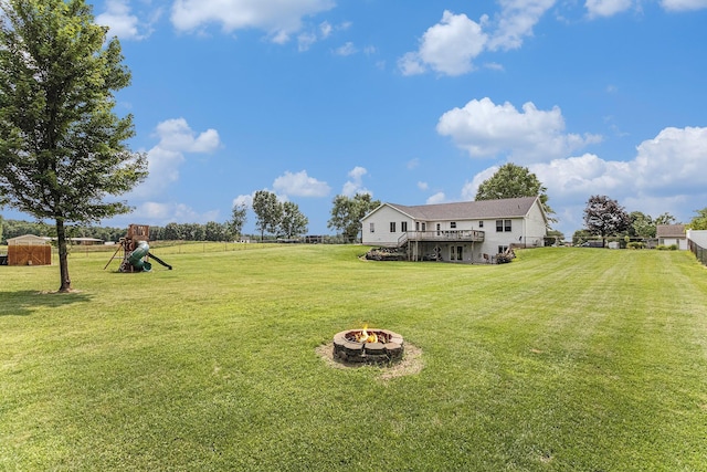 view of yard featuring a deck, a fire pit, and a playground