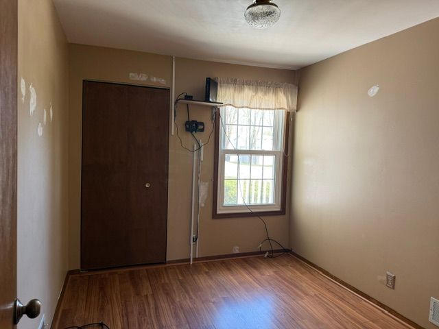 unfurnished room featuring wood finished floors, visible vents, and baseboards
