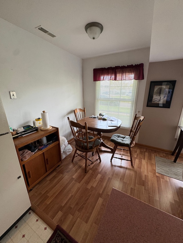 dining area with light wood-type flooring, visible vents, and baseboards