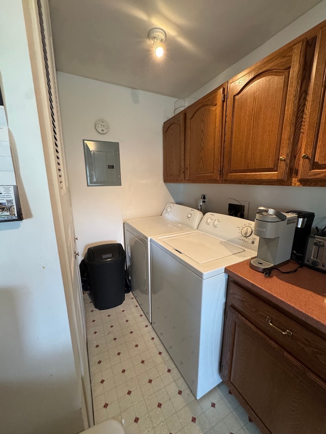 washroom featuring electric panel, separate washer and dryer, light floors, and cabinet space