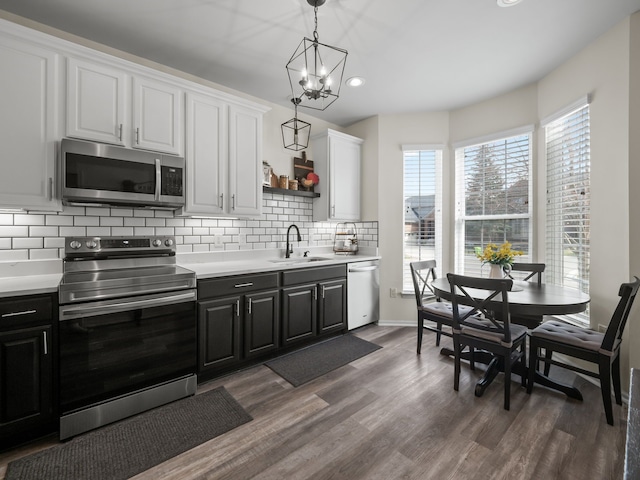 41698 Brownstone Dr, Novi, MI 48377 - kitchen featuring white cabinets, a sink, dark wood finished floors, decorative backsplash, and appliances with stainless steel finishes