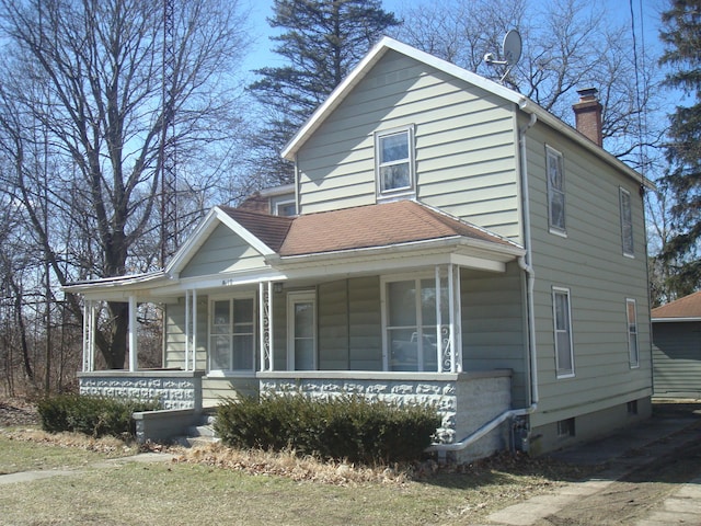 view of front of home featuring a porch, a chimney, and a shingled roof