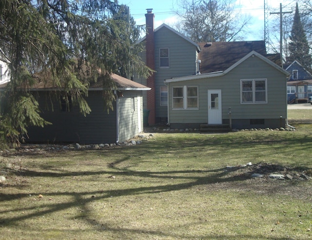 rear view of house with a lawn, a chimney, and entry steps
