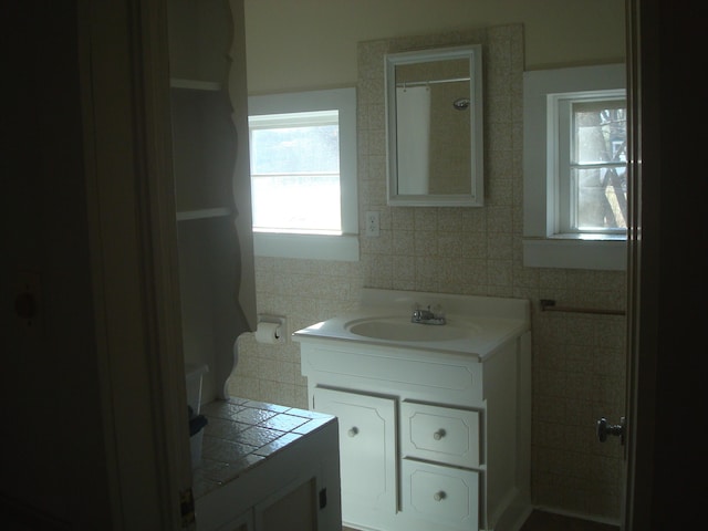 full bathroom featuring tile walls and vanity