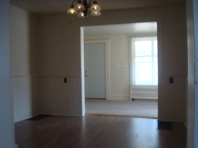 spare room featuring a chandelier, radiator heating unit, and wood finished floors
