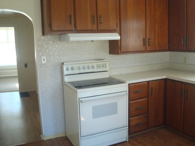 kitchen with radiator, dark wood finished floors, white electric range, under cabinet range hood, and light countertops
