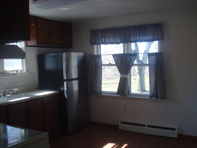 kitchen featuring baseboard heating, a sink, a wealth of natural light, dark wood finished floors, and freestanding refrigerator