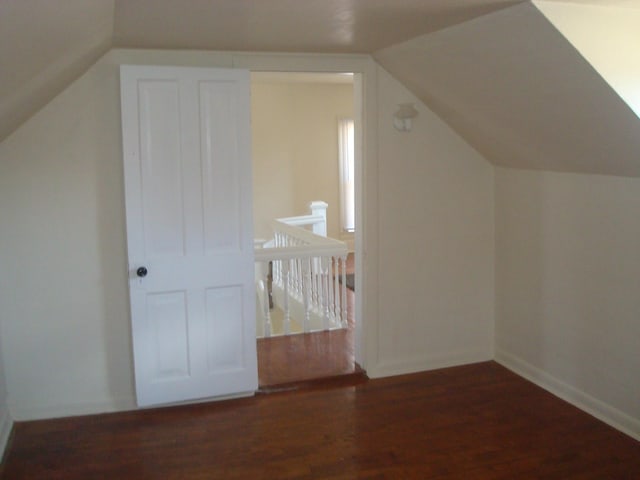 additional living space with vaulted ceiling, wood finished floors, and baseboards