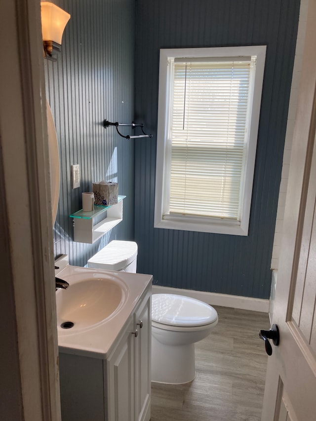 bathroom with baseboards, wood finished floors, vanity, and toilet