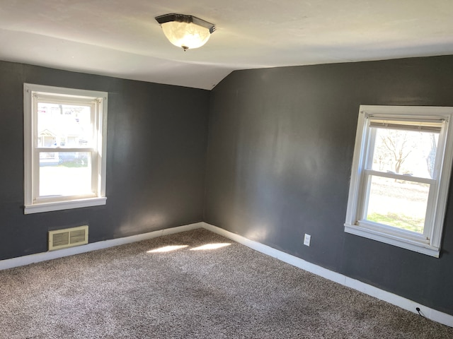 spare room with carpet, visible vents, lofted ceiling, and baseboards