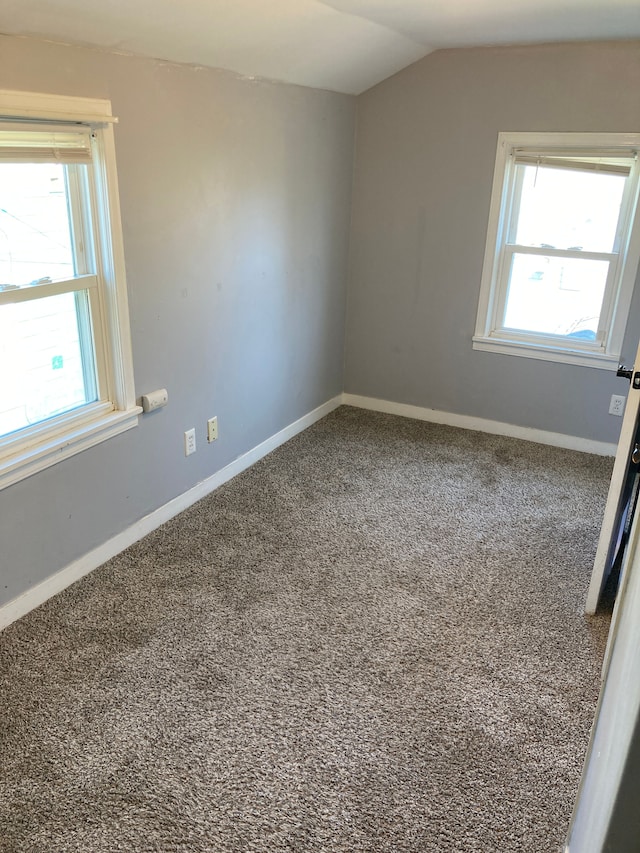 spare room featuring plenty of natural light, vaulted ceiling, and carpet