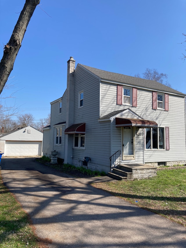 view of front of house with an outdoor structure, a chimney, and a detached garage