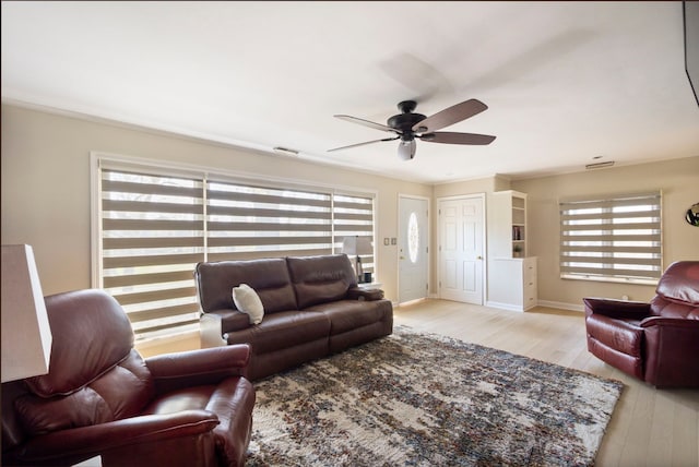 living room with visible vents, ceiling fan, light wood finished floors, and baseboards